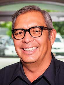 Northern NV SME Monthly Meeting - November 3 Smiling middle-aged man with short gray hair and black glasses, wearing a dark shirt, stands indoors with cars in the background at the Northern NV SME November monthly meeting.