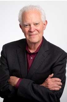 An older man with white hair in a dark suit jacket and maroon shirt stands with arms crossed, smiling at the camera against a plain light background—ready for the Northern NV SME monthly meeting this September.